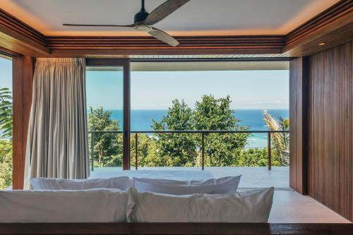 a bedroom with a bed and a large window at Tampah Hills in Selong Belanak