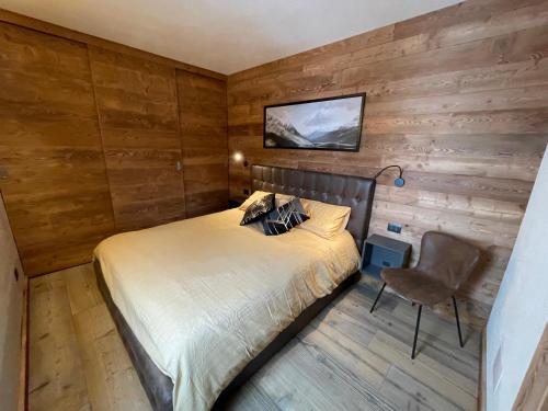 1 dormitorio con paredes de madera, 1 cama y 1 silla en Apartment Gran Baita Sauze d'Oulx, en Sauze dʼOulx