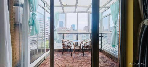 a balcony with a table and chairs in a room with windows at Top floor sunny bedroom near Fudan in Shanghai
