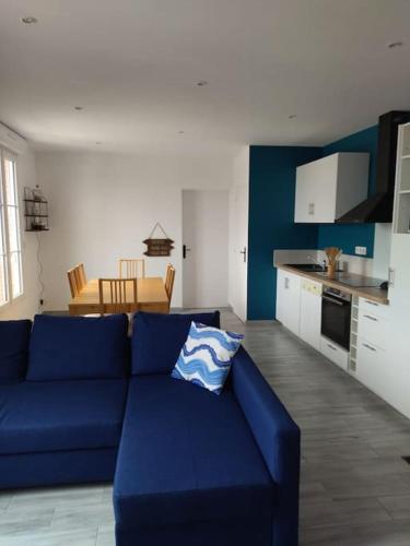 un salon avec un canapé bleu et une cuisine dans l'établissement Grain de café Barneville Plage, à Barneville-Carteret