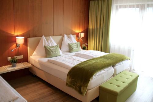een slaapkamer met een groot bed met een groene deken erop bij Hotel Montana in Telfes im Stubai