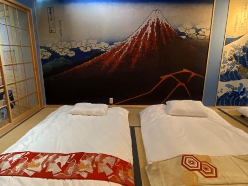 two beds in a room with a painting on the wall at Osaka Ukiyoe Ryokan in Osaka