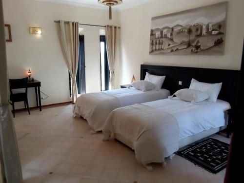 2 camas en una habitación de hotel con sábanas blancas en Le petit Château des Anges, en Marrakech