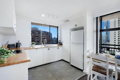 Una cocina con gabinetes blancos y una ventana grande. en Central Getaway With Ocean Views - CoastHM, en Gold Coast