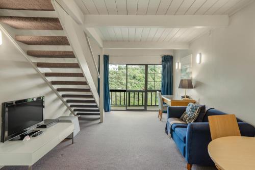 a living room with a blue couch and a staircase at Capital Lodge Motor Inn in Wellington