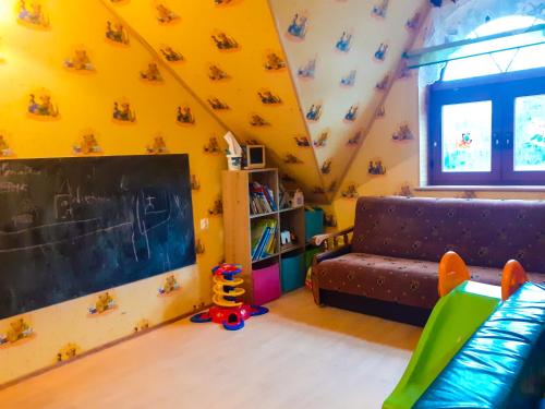 a yellow room with a couch and a chalkboard at Agroturystyka Pod Złotą Wiechą in Uście Gorlickie