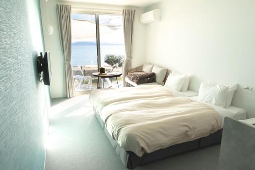 a bedroom with a large bed with a large window at SETOUCHI SUP RESORT - Ao - in Shodoshima
