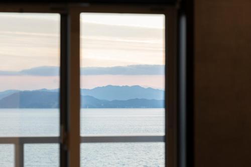 a window with a view of the water and mountains at SETOUCHI SUP RESORT - Ao - in Shodoshima