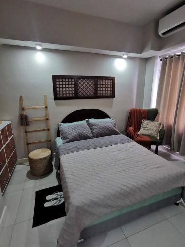a bedroom with a large bed and a chair at Baseline Premier - Studio with mountain view in Cebu City