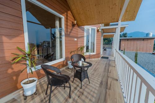 a patio with two chairs and a table on a porch at SaffronStays Cottage Glade, Dehradun - luxury wooden cottage in Dehradun