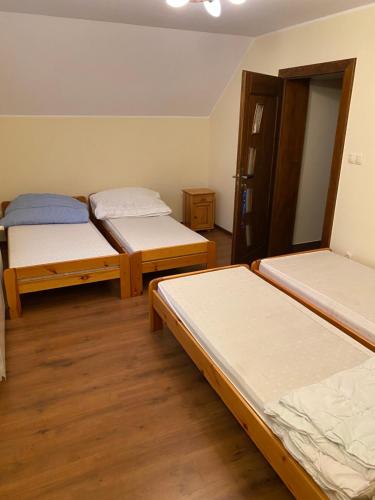 three beds in a room with wooden floors at Dom Wiktor in Tarnowiec
