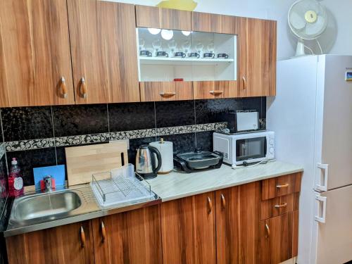 een keuken met houten kasten, een wastafel en een koelkast bij Apartman Hrastik 2 in Bihać