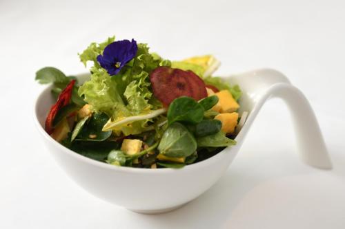 a white bowl filled with a salad with a purple flower at Hôtel Domaine de la Sauge in Cudrefin