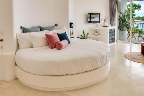 a large white bed with pillows on it in a room at Ampersand Resort in Bophut 