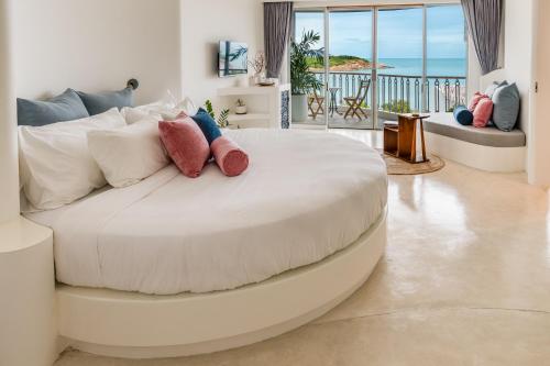 a large white bed with pillows in a living room at Ampersand Resort in Bophut 