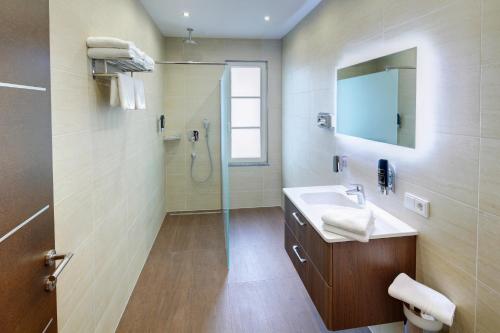 a bathroom with a sink and a shower with a mirror at Hotel Füssen in Füssen
