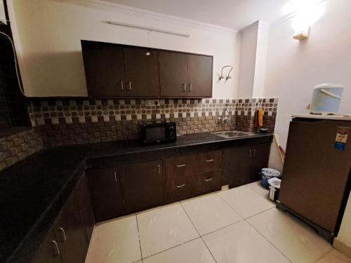 a kitchen with brown cabinets and a black counter top at Private room with Sky Garden in Green Bacchus by Walias in Gurgaon