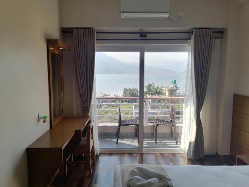 a bedroom with a bed and a balcony with a view at Urban Boutique Hotel Pokhara in Pokhara
