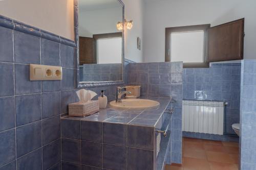 Baño de azulejos azules con lavabo y espejo en Casa Rural El Abuelo Luis, en Molinicos