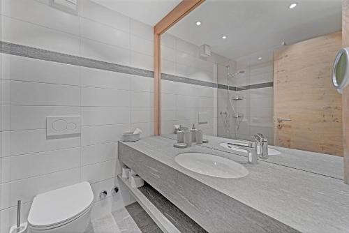 een badkamer met een wastafel, een toilet en een spiegel bij Guardalej 321 in Champfer