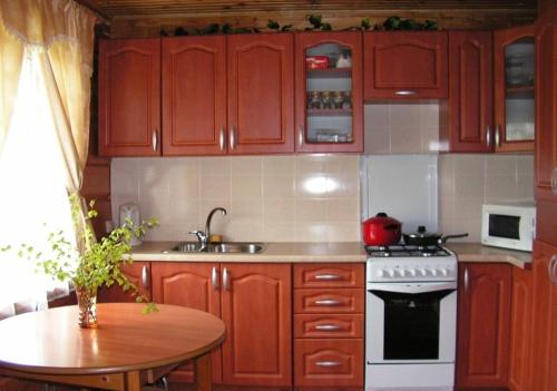 a kitchen with wooden cabinets and a table and a stove at Pakrasti in Svente