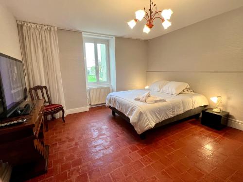 Dormitorio con cama, escritorio y TV en * La Petite Ferme de Moiry * Maison Indépendante proche du circuit de Magny Cours en Saint-Parize-le-Châtel