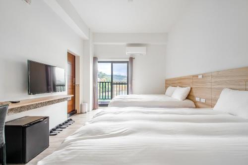 two beds in a hotel room with a flat screen tv at Sun Moon Lake I Love You in Yuchi