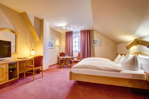 a hotel room with a bed and a desk at Hotel Landhaus Steinfeld in Greetsiel