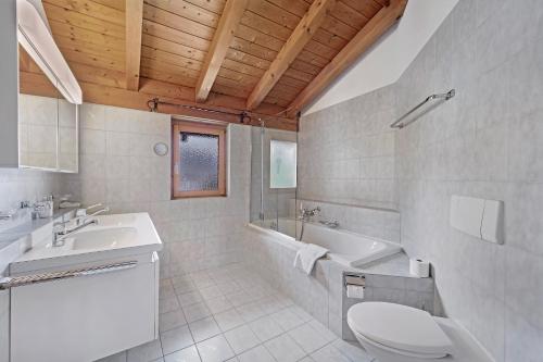 Un baño con inodoro, lavabo y bañera. en Anda 6, en Celerina