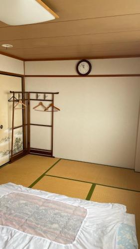 Habitación con cama y reloj en la pared en はらビジネス旅館 en Wakayama