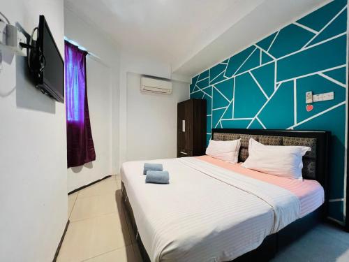 a bedroom with a large bed with a blue wall at MJ inn in Ranau