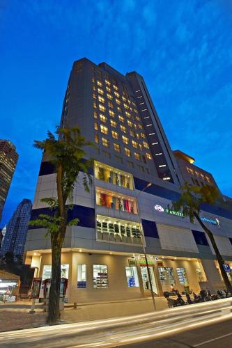 a tall building with a palm tree in front of it at Metrostar Hotel Kuala Lumpur in Kuala Lumpur