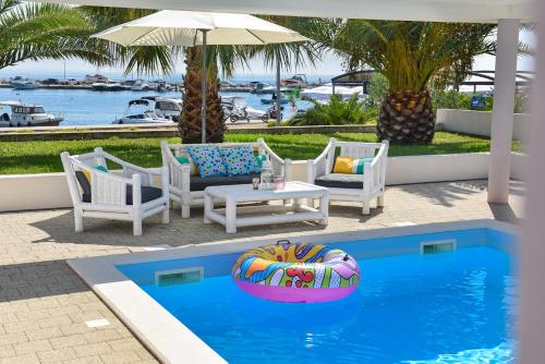uma piscina com cadeiras, uma mesa e um guarda-sol em Apartments Bella Sky III/IV em Novalja