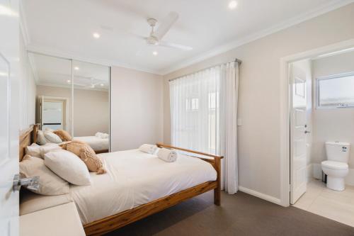 a white bedroom with a bed and a mirror at AZZURE on WATERVILLE in Dunsborough