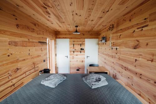 1 dormitorio con 1 cama en una pared de madera en La cabane de la Ferme du Ry en Sorinnes