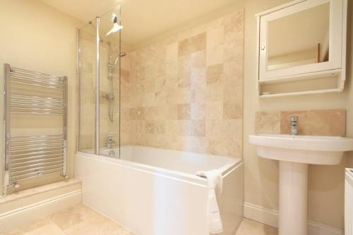 a bathroom with a tub and a sink and a shower at Farne View Cottage in Seahouses