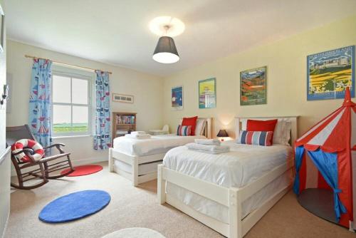 a bedroom with two beds and a chair in it at Farne View Cottage in Seahouses
