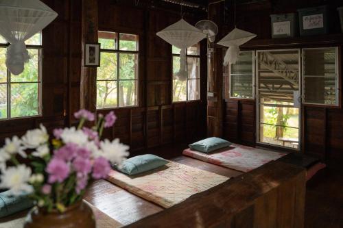 a room with a table with flowers and windows at Art House at Chiangdao - Waterlily House in Chiang Dao