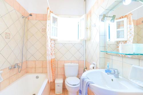 y baño con bañera, aseo y lavamanos. en Alexandra Bay Front, en Ágios Stéfanos