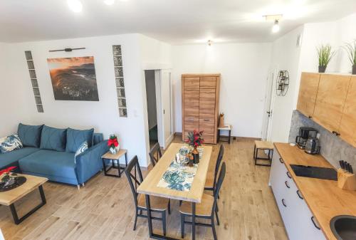 a living room with a blue couch and a table at Dusznickie Apartamenty z widokiem in Duszniki Zdrój