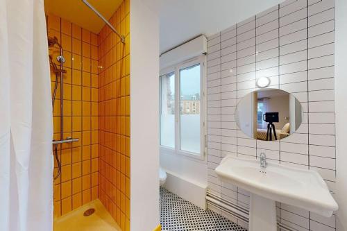 La salle de bains est pourvue d'un lavabo, d'un miroir et d'une baignoire. dans l'établissement Maison 12 chambres en plein coeur du Havre, au Havre