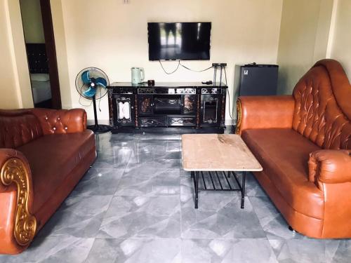 Sala de estar con 2 sofás de cuero y mesa de centro en Thomas' Retreat Bukit Lawang, en Bukit Lawang