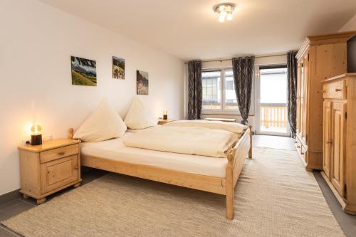 a bedroom with a large bed and a large window at Ferienwohnungen Müggelberge in Oberstdorf