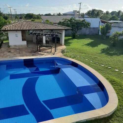 a large blue swimming pool in front of a house at CASA ESTRELA e SOL in Barra de Jacuípe