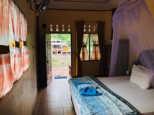 a bedroom with a bed and a door to a yard at Thomas' Retreat Bukit Lawang in Bukit Lawang