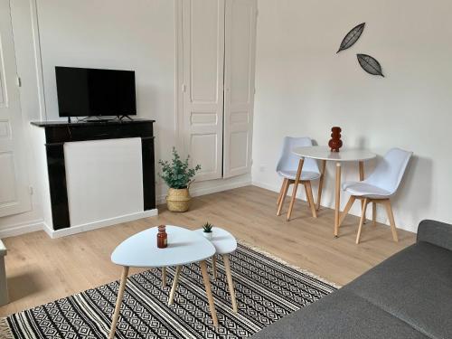 a living room with two tables and a tv at Florimond cosy apparts in Saint-Quentin