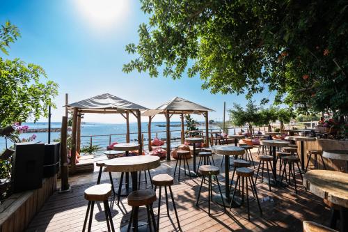 a row of tables and stools on a deck near the water at Golden Coast Beach Hotel in Protaras