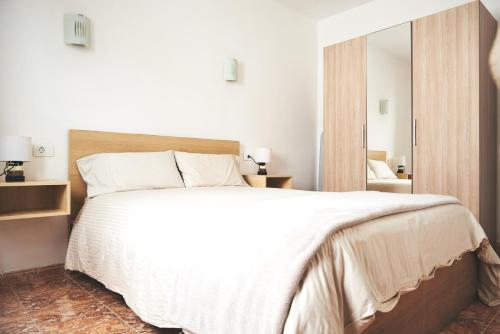 1 dormitorio con 1 cama blanca grande y espejo en Casa Mar adentro, en La Santa