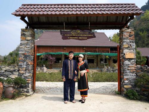a man and a woman standing in front of a building at Nasan Green Farm in Cao Bằng