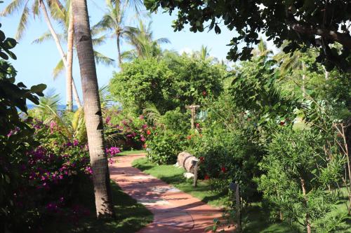a path through a garden with flowers and palm trees at Island View Beachfront Resort in Anda